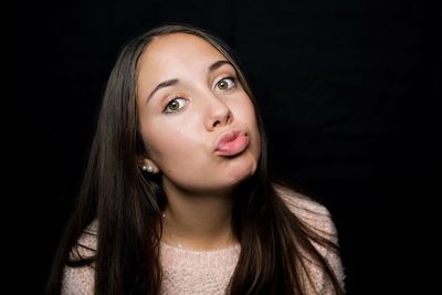 Portrait of beautiful woman puckering lips against black background