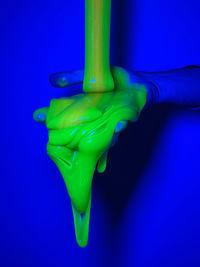 Cropped hand of person cleaning brush against blue background