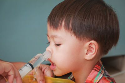 Cropped hand spraying water in boy nose