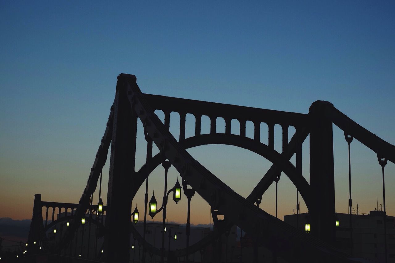 clear sky, silhouette, built structure, sunset, low angle view, architecture, connection, copy space, bridge - man made structure, engineering, sky, dusk, metal, bridge, blue, railing, outdoors, sunlight, no people, nature