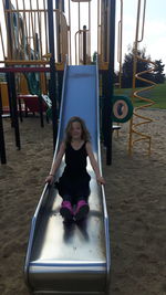 Full length of girl sitting on slide in playground