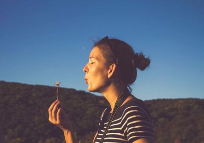 Young woman smoking against sky