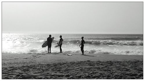 Surfers standing on shore at beach