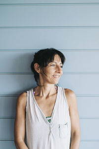 Smiling woman standing against wall