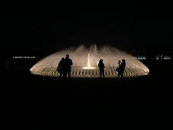 Rear view of silhouette people standing at night