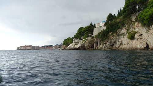 Scenic view of sea by buildings against sky