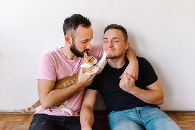 Gay couple playing with kitten.