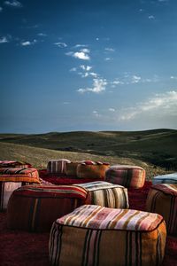 Lounge chairs on sofa in field against sky