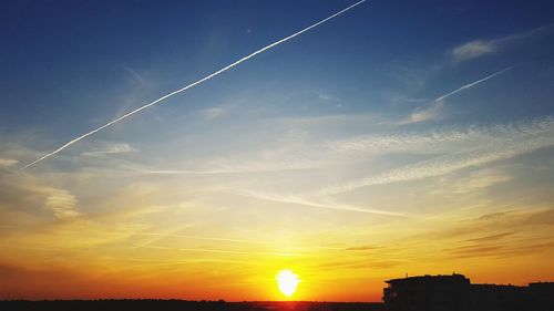 Low angle view of vapor trails in sky during sunset