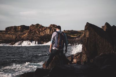 Woman standing on rock by sea