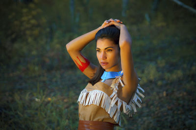 Portrait of young woman standing against tree