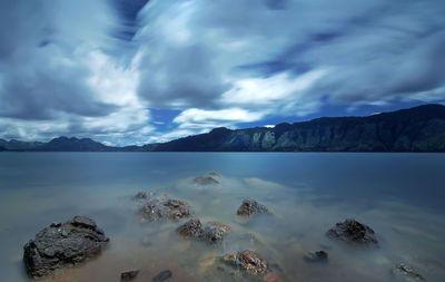 Panoramic view of sea and mountains against storm clouds
