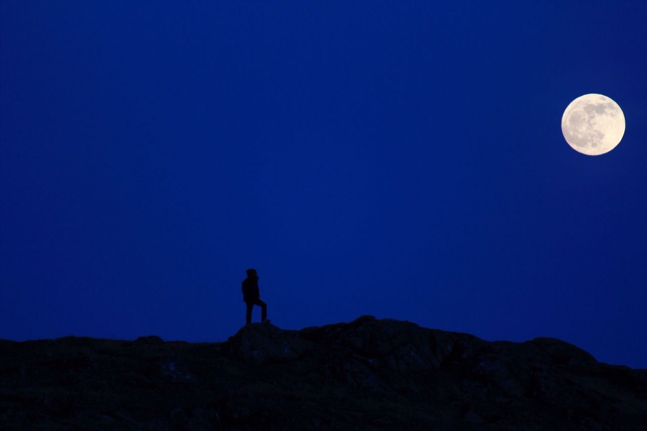 copy space, clear sky, blue, moon, leisure activity, lifestyles, silhouette, tranquil scene, tranquility, standing, scenics, night, mountain, exploration, full length, beauty in nature, men, discovery