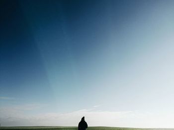 Silhouette man standing by sea against clear blue sky