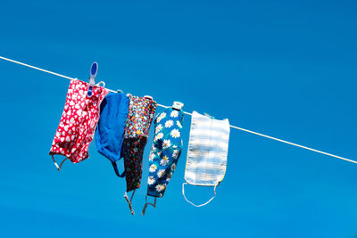 Low angle view of clothes hanging on clothesline against blue sky