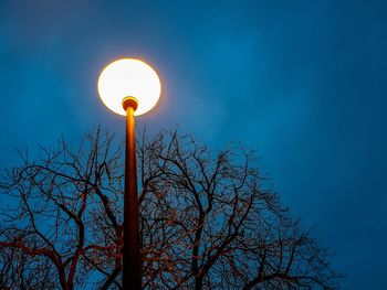 Low angle view of illuminated street light against blue sky