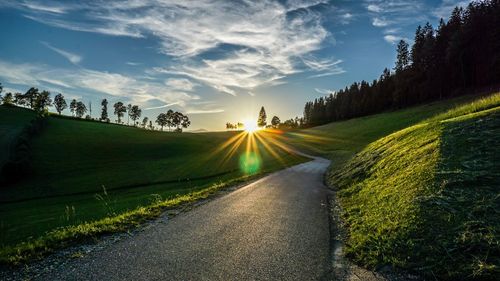 Road amidst green landscape against sky