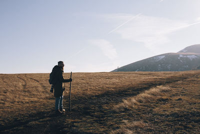 Side view  of man on landscape against sky