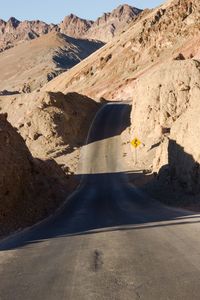 Shadow on road by mountain against sky