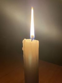 Close-up of lit candle in darkroom