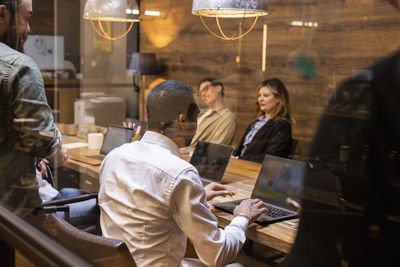 Businessman using laptop while sitting in board room with colleagues during meeting