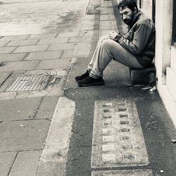 Man sitting on footpath