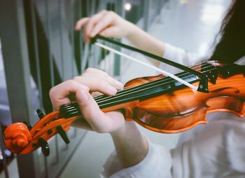 Midsection of female violinist playing violin by fence