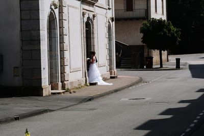 Woman standing on street amidst buildings in city