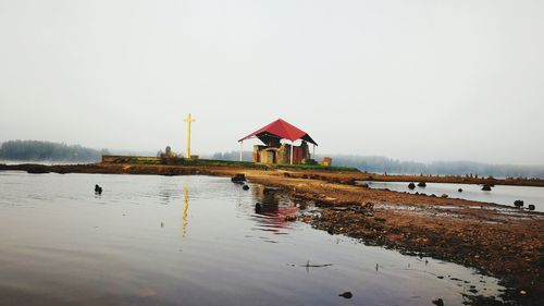 Stilt house on lake against clear sky