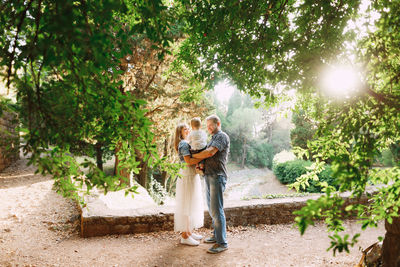 Couple kissing with plants against trees