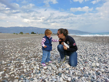 Woman playing with daughter at beach 