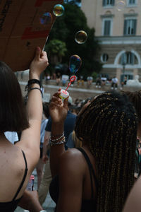 Rear view of women holding bubbles in city