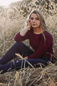 Portrait of young woman sitting on field