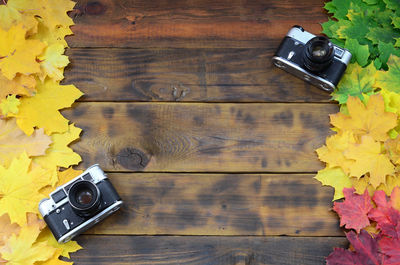 High angle view of cameras and autumn leaves on table