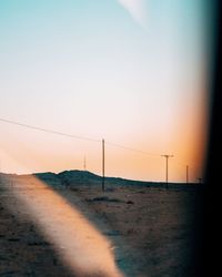 Electricity pylon on land against sky during sunset