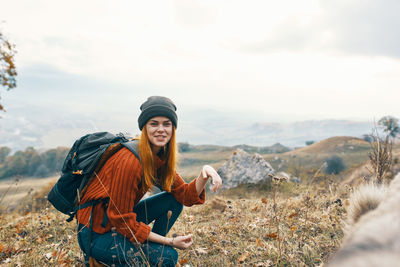 Young woman wearing hat on rock against sky