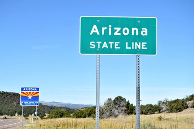 Information sign by road against blue sky