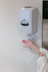 Midsection of woman holding mobile phone against wall
