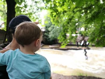 Father and son against trees in sunny day