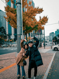 Couple with arms raised making heart shape while standing on street