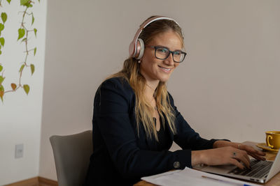 Woman working at home with laptop and papers on desk and headphones. home office . gray notebook 