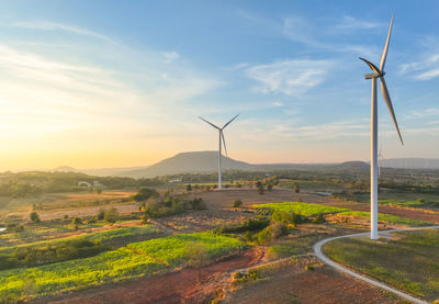 Windmills on field against sky during sunset