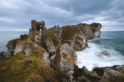 Rock formation on beach against sky