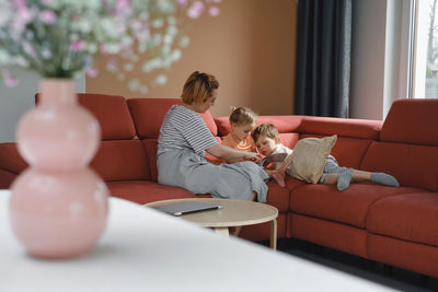 Mother reading book with two kids on sofa. happy family moments at home. spending time and educating