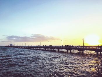 Pier over sea against sky during sunset