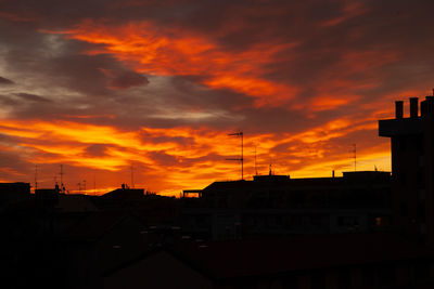 Silhouette buildings against orange sky