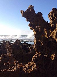 Close-up of sea waves splashing on rocks against clear sky