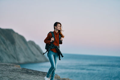 Young woman standing in sea against sky