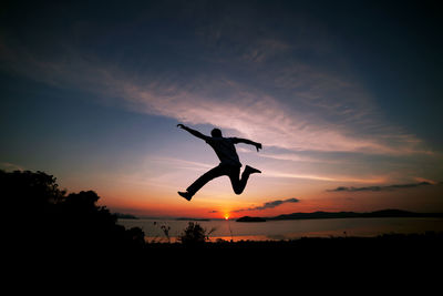 Silhouette man jumping against sky