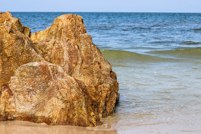 Rock formation on beach against sky